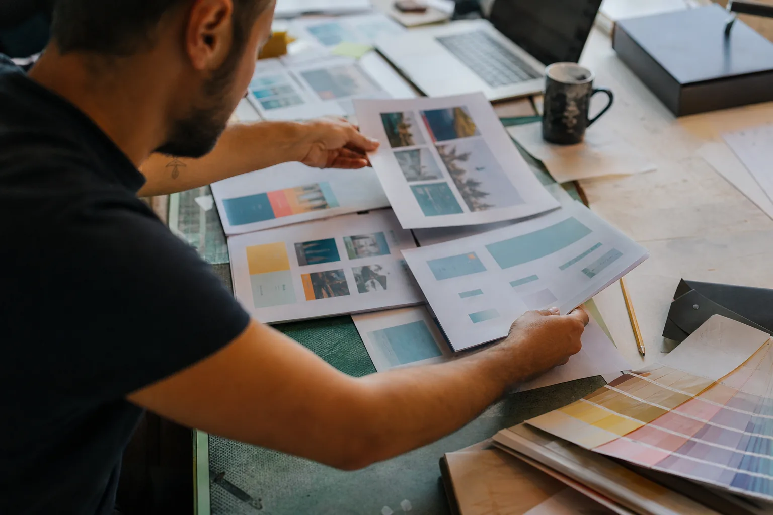 Designer reviewing a printed website layout on a light table in a small studio